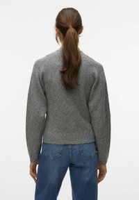 Suéter gris de punto con un escote redondeado, textura acanalada y costuras de hombro caídas, combinado con jeans de mezclilla azul.