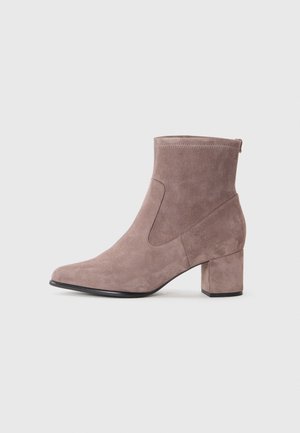 Bottine en daim taupe avec un bout arrondi, un talon bloc et des détails de couture latérale sur un fond clair uni.