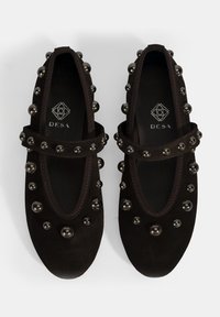 Schwarze Wildlederschuhe mit runder Zehenform, Mary-Jane-Riemen und metallischen Nieten entlang der Ränder. Innen befindet sich das Logo der Marke "DESA."