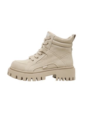 Beige høyt lærredsstøvel med tykk, klumpete såle, snøring foran, polstret ankelkrage og løkke ved hælen for enkel påtrekking.