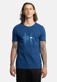 Camiseta azul de manga corta hecha de algodón con un diseño gráfico de onda sonora en azul y púrpura en el pecho. Corte ajustado.