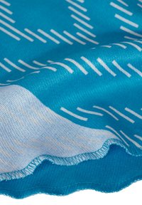 Textiel met een blauwe achtergrond waarop een diagonaal wit lijnpatroon te zien is. De stof heeft een zachte textuur en gegolfde randen.