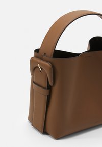 Borsa in pelle marrone con una forma strutturata, manico arrotondato corto e un bordo nero a contrasto. Presenta un dettaglio a fibbia piatta sul lato.