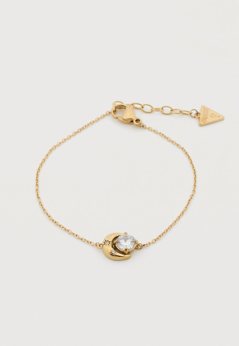 Λεπτό βραχιόλι χρυσής αλυσίδας με κρεμαστό σε σχήμα ημισελήνου που κρατάει στρογγυλό διαφανές πολύτιμο λίθο και μικρές λεπτομέρειες αστεριού, ρυθμιζόμενο κούμπωμα με ταυτότητα σε σχήμα τριγώνου.