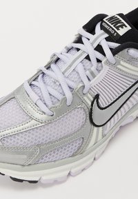 Nike Vomero 5 Laufschuh mit einem Obermaterial aus Netz und Synthetik in Silber und Lavendel, mit schwarzen Akzenten und einer strukturierten Sohle.
