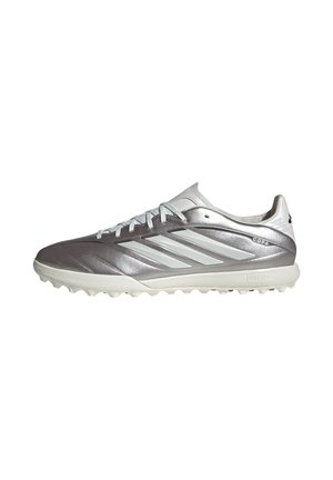 Scarpa da calcio bassa color argento e bianco con tre strisce bianche, lacci, suola strutturata e marchio "COPA" sul lato.