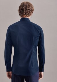 Dunkelblaues Langarmshirt aus glattem Stoff mit tailliertem Schnitt, ausgestattet mit einem klassischen Kragen und geknöpften Manschetten.