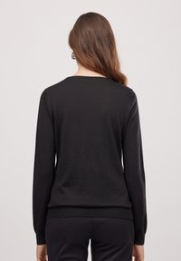 Schwarzer, langärmeliger Pullover mit rundem Halsausschnitt und geripptem Saum, aus weichem Stoff. Die Rückseite hat eine glatte Textur ohne Muster.