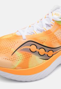 Bright orange running shoe with a mesh upper, white laces, and a black wave logo. Features a cushioned sole and textured patterns.