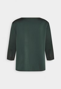 Dunkelgrüne Bluse mit geradem Schnitt, Dreiviertelärmeln und glatter Textur. Einfaches Design ohne sichtbare Muster oder Metallteile.