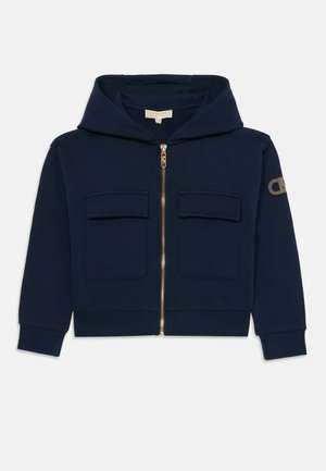 Sudadera azul marino con cremallera completa en la parte delantera, dos bolsillos en el pecho y puños acanalados. Adornada con un logo en la manga con detalles en dorado.