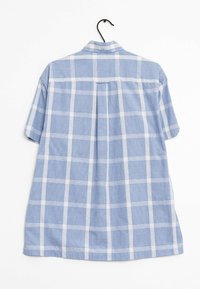 Kort-gemouwde lichtblauwe geblokte shirt met wit rasterpatroon, achterpasse seam detail en een kraag; stof lijkt zacht en gestructureerd.