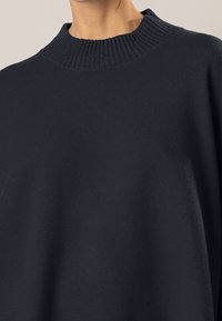 Pull navy blue con un alto collo a coste, realizzato in materiale morbido, con una vestibilità ampia e un design minimalista.