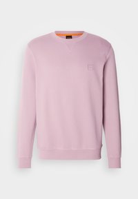Sweat-shirt rose clair à manches longues avec col rond, poignets et ourlet côtelés, petit logo carré embossé sur la poitrine gauche.
