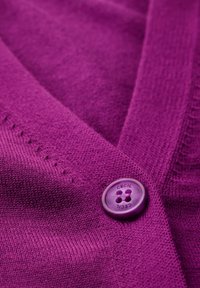 Pull violet en tricot avec un design en V, comportant un bouton brillant étiqueté "CECIL" et des détails subtils de texture en maille.