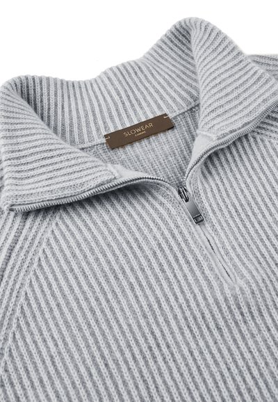 Grau geripptes Strickpullover mit einem Reißverschluss am Hals, ausgestattet mit einem umgeschlagenen hohen Kragen und einem braunen Etikett, auf dem "SLOWEAR" steht.