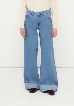 Vide jeans i lys blå denim, med høy midje, to frontlommer og løs passform. Oppbrettede ender strekker seg forbi skoene.