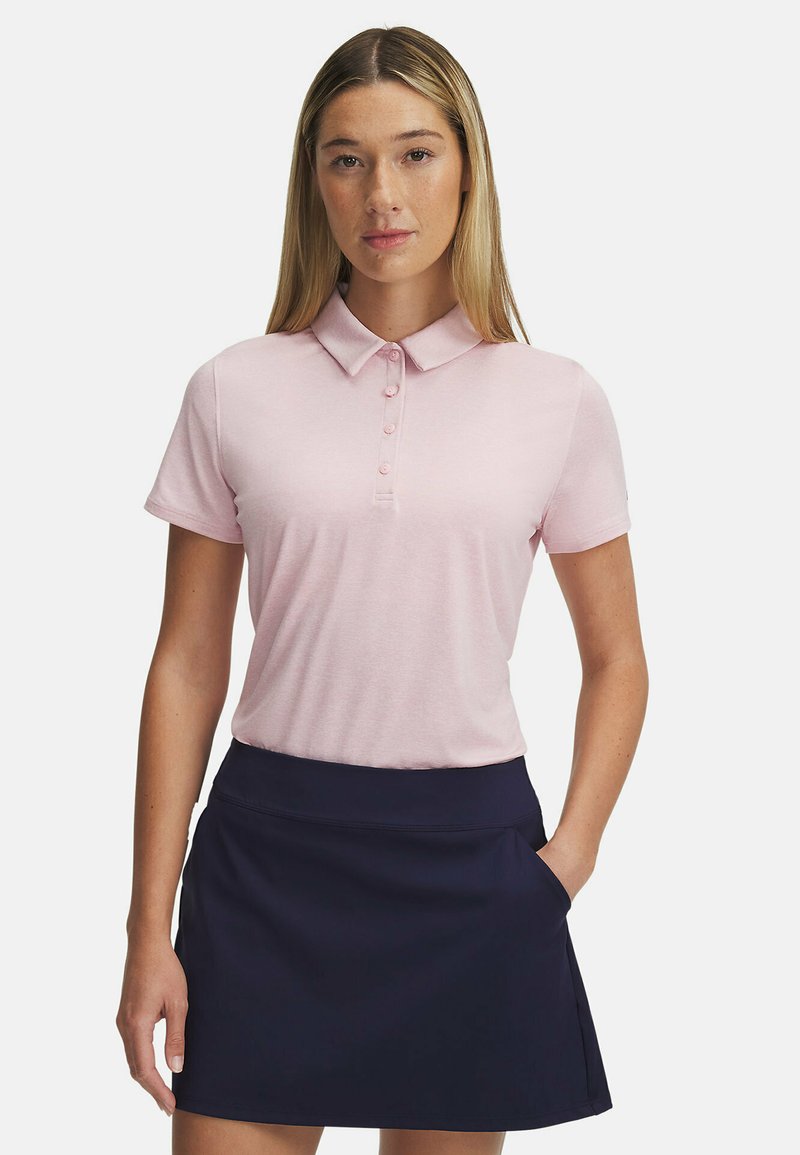 Ljusrosa polo-tröja med krage och knapplist, kombinerad med en marinblå kjol med ficka. Slätt tyg med en avslappnad passform.