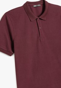 Bordeaux polo-shirt lavet af tekstureret stof, med en mesh krave og to knapper, korte ærmer og subtile syninger.