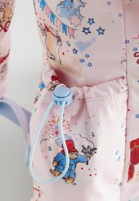 Šnervinė maišelį su šviesiai rožiniu audiniu, ant kurio pavaizduoti spalvingi gyvūnų, žvaigždžių ir debesų piešiniai. Matomas mėlynas šnervinis uždarymo detalė.