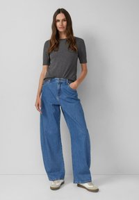 Grijs T-shirt met korte mouwen gecombineerd met losse, lichtblauwe spijkerbroek. De jeans hebben een hoge taille en een klassiek vijf-pocket ontwerp.