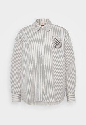 Chemise à boutons en coton blanc avec de fines rayures verticales bleues, dotée d'un col structuré et d'une accent en tissu en forme de fleur sur la poitrine gauche.