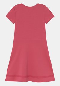 Różowa bawełniana sukienka w kształcie T-shirtu z krótkim rękawem, okrągłym dekoltem i rozkloszowanym dołem, z falbaniastym wykończeniem na dole.