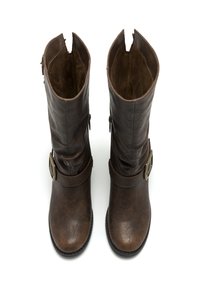 Une paire de bottes en cuir marron élevées avec des fermetures éclair latérales et des boucles en laiton décoratives, présentées de dessus sur un fond blanc.