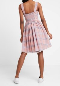 Różowa sukienka w kratę z szerokimi ramiączkami, dopasowanym gorsetem i rozkloszowanym dołem, charakteryzująca się gładką fakturą i bezplecą.