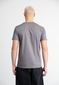 T-Shirt mit kurzen Ärmeln und Rundhalsausschnitt aus hellgrauer Baumwolle, mit glatter Textur und lockerer Passform. Rückansicht zeigt ein schlichtes Design ohne Muster.