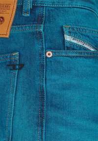 Tyrkysové džíny z denimu s výrazným švem, malou přední kapsou a značkovou vnitřní etiketou. Výrazné texturované vzory po celém povrchu.