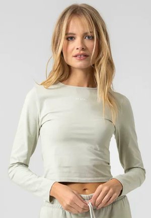 Langermet, lys grønn crop top laget av glatt stoff med en tettsittende design. Har rund hals og subtil tekst på brystet.