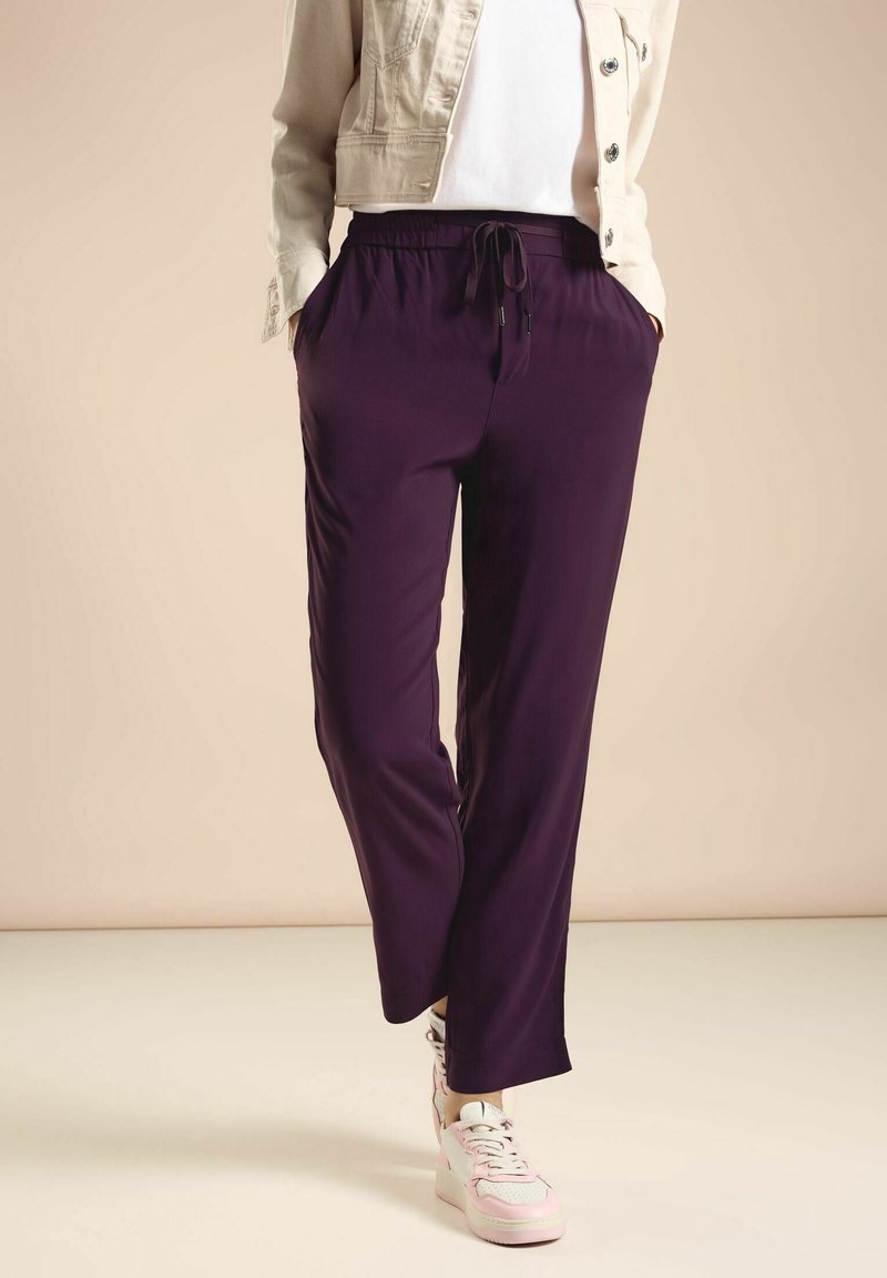 Lila, lätta joggerbyxor med elastisk midja, dragsko och sidofickor. Sammanvävt med vita sneakers och en lätt jacka.