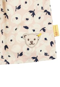 Stoff mit floralem Muster in sanftem Rosa, verziert mit weißen und marineblauen Blumen. Enthält einen gestickten Bärenkopf mit gelben Akzenten. Aus Baumwolle.