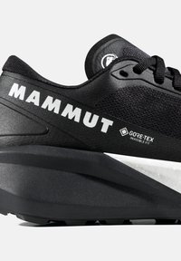 Czarny but biegowy Mammut z tkaniną Gore-Tex Invisible Fit, grubą podeszwą i sznurowanym zapięciem, ze szczególnym uwzględnieniem detali bocznych i tylnych.