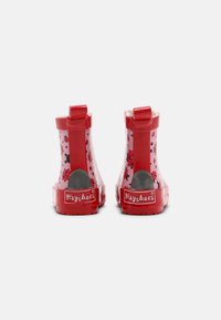 Rote Gummiregenstiefel mit einem Marienkäferdesign, strukturierten Oberflächen und einem Logo auf der Ferse. Mit einem Ziehband für ein einfaches Anziehen.