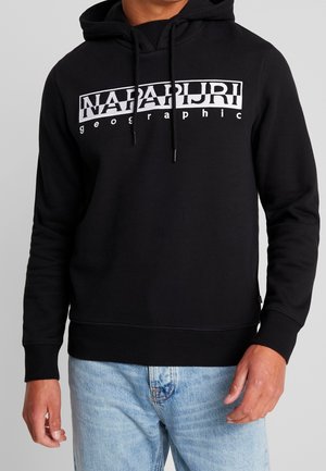 Czarna bluza z kapturem z białym logo „NAPAPIJRI geographic” na piersi, noszona z jasnoniebieskimi dżinsami przez osobę.