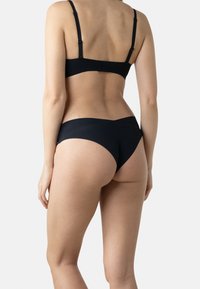 Ensemble de soutien-gorge noir et sous-vêtements assortis en tissu lisse. Le soutien-gorge a des bretelles ajustables et un design simple sans coutures.