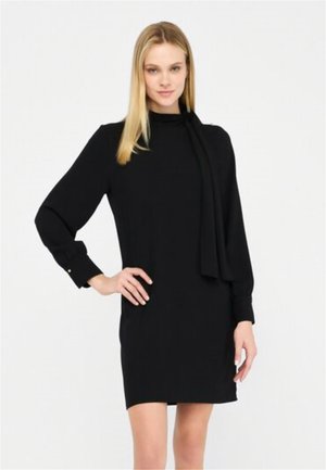 Abito nero con maniche lunghe, collo alto e dettaglio foulard. Presenta polsini con bottoni e una silhouette slanciata. Texture liscia.