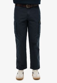 Marine cargo bukser med to sidelommer, justerbare ankle cuffs og et brunt bælte. Båret med hvide og beige sneakers.