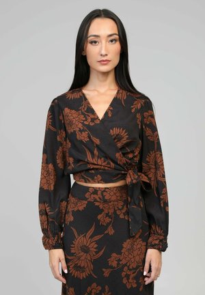 Haut noir à manches longues, avec un motif floral marron. Tissu doux et silhouette ajustée avec un détail de lien à la taille.