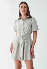 Hellgraues Kurzarmkleid mit Kragen, Knopfverschluss vorne, gefälteltem Taillenbereich und A-Linie Rock. Glatte Textur des Stoffes.