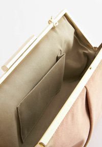 Torebka kopertówka z złotym metalowym wzmocnieniem; zewnętrzna strona z miękkiego różowego materiału; beżowa podszewka z materiału z kieszonką na suwak. Zamykanie na klamerkę.