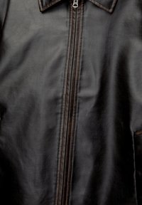 Veste en cuir marron foncé avec une fermeture éclair à l’avant et un col pointu, montrant la texture naturelle du cuir et les détails de couture.