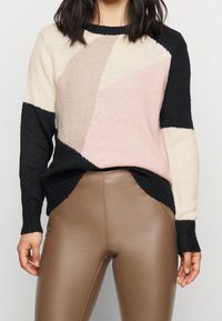 Mehrfarbiger Pullover mit geometrischem Muster in Creme, Pink und Schwarz, aus weichem Strickstoff mit gerippten Bündchen und Saum.