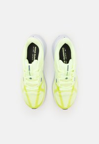 Baskets de course Nike avec une tige en maille jaune vif, semelle blanche, col rembourré et semelle intérieure noire, dotées de minimalistes accents bleus.