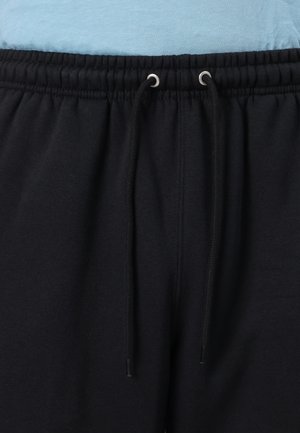 Pantalon de sport noir avec une taille élastique et un cordon de serrage. Le tissu semble doux avec une texture lisse, adapté pour un port décontracté.
