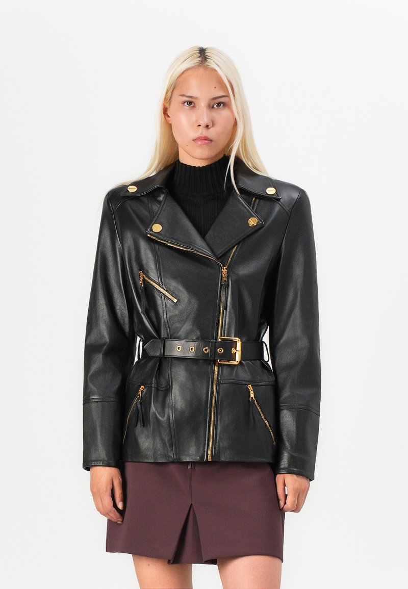 Black leather jacket with gold hardware, zippered pockets, and a belted waist. Features a classic lapel and smooth texture.