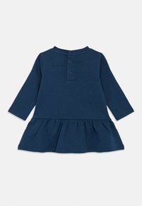 Μακρυμάνικο φόρεμα σε ναυτικό μπλε χρώμα με στρογγυλή λαιμόκοψη, κλείσιμο με κουμπιά στην πλάτη και φούστα με σούρες. Ομαλό ύφασμα με απαλή υφή.