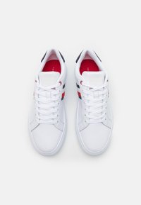Weiße Sneakers mit Obermaterial aus synthetischem Leder, Schnürverschluss, rot-blauen Streifen, gepolsterter Knöchelpartie und Gummisohle. Logo auf der Zunge.